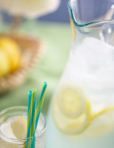 A pitcher and glass of lemonade with straws